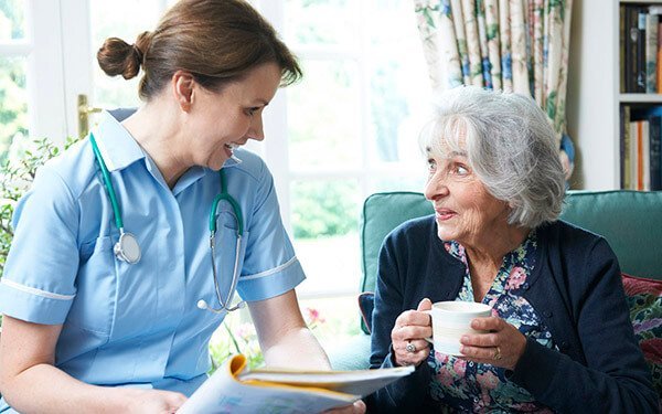 Nurse Discussing Medical Notes With Senior Woman At Home