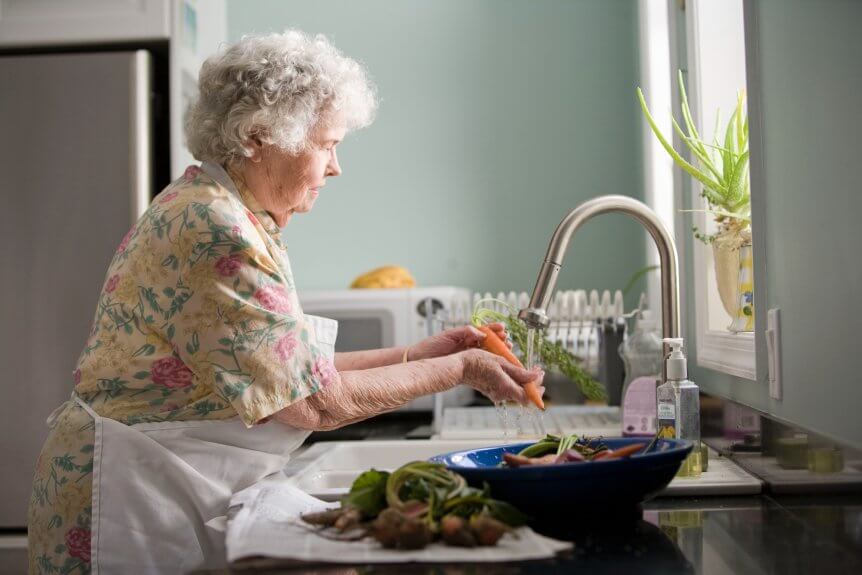 elderly woman wahing vegetables